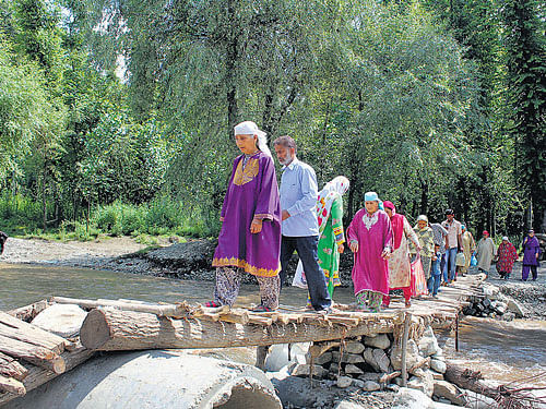 Villagers cross Chandri river usingmakeshiftwooden bridge at Chandrigamin south Kashmir's Pulwama district on Thursday. The concrete bridge and some other foot bridges on the riverwerewashedaway recently. PTI