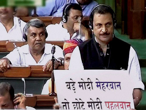 An opposition member holding a placard in front of MoS Rajiv Pratap Rudy during a protest in the Lok Sabha in New Delhi on Wednesday during the monsoon session. PTI Photo