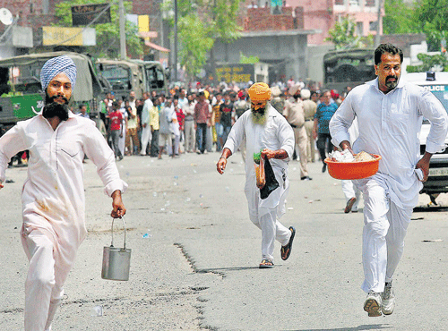Residents run near the site of a gunfight at a police station at Dinanagar town