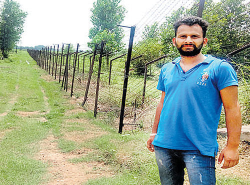 A man stands near the fence on the Punjab-Pakistan border in Jaidpur village in Gurdaspur district. DH PHOTO