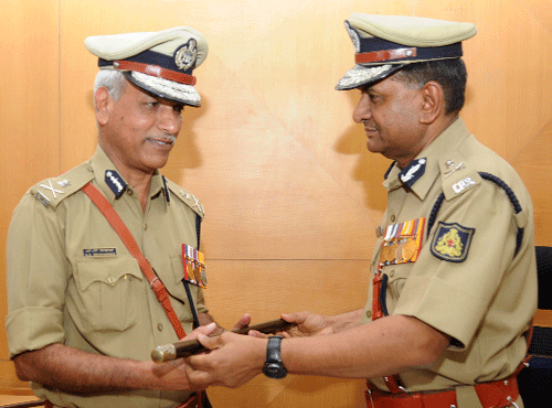 CHANGE OFGUARD:Outgoing commissioner of police MNReddi (right) hands over the baton to NS Megharikh, in the City on Friday. DH PHOTO