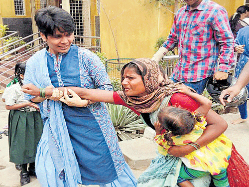 Geetha Kulkarni, a CCB inspector in plain clothes, detains a woman who was begging in the City on Thursday. DH photo