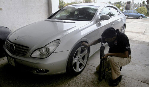 A police officer examines the car of Pakistan's former cricket captain Wasim Akram after a a gun attack at National Stadium in Karachi, Pakistan, Wednesday, Aug. 5, 2015. Akram said he was on his way to the sports stadium when a man rammed his vehicle into his car and then opened fire before fleeing. AP photo