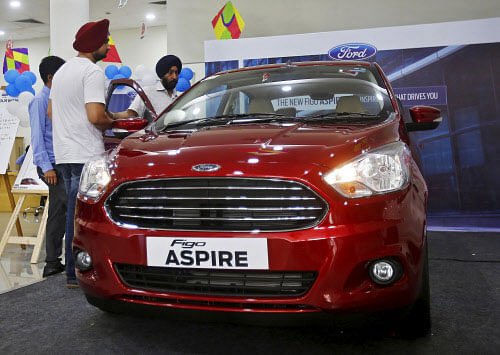 Customers inspect Ford's new Figo Aspire car on display at a showroom in New Delhi. Reuters