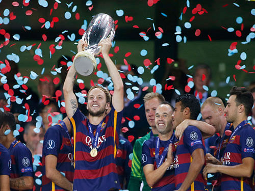 Barcelona's Ivan Rakitic holds up the trophy near team mates as they celebrate their victory over Sevilla in the UEFA Super Cup soccer match at Boris Paichadze Dinamo Arena in Tbilisi, Georgia, August 12, 2015. REUTERS.