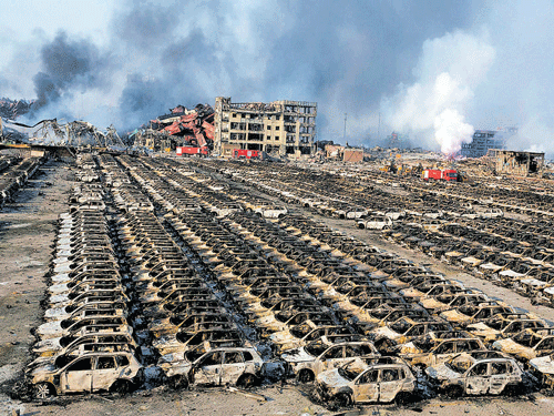 Devastation: Smoke billows from the site of an explosion that destroyed a parking lot filled with new cars at a warehouse in Tianjin, China, on Thursday. AP/PTI