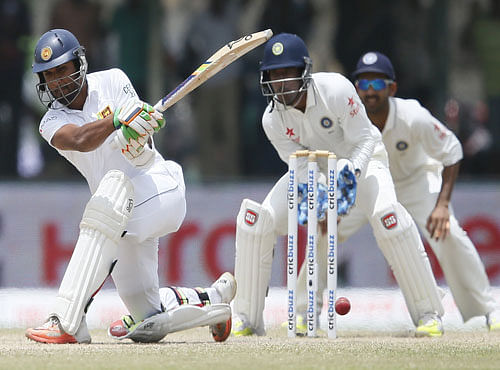 Sri Lanka's Chandimal hits a boundary next to India's wicketkeeper Saha and Rahane during the third day of their first test cricket match in Galle. Reuters photo
