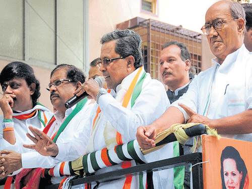 Chief Minister Siddaramaiah addressing voters as part of the road show organised for the Congress candidate Janaki Ram at Domlur on Friday. KPCC President Parameshwara and AICC Karnataka In-charge Digvijaya Singh are with him. DH PHOTO