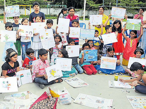Children from the neighbourhood show off their paintings at the Deccan Herald Painting and Quiz competition in the Koramangala Park on Saturday. DH PHOTO