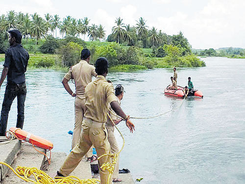 Rescue workers search for the bodies of two teenagers, who drowned while immersing their grandfather's ashes in the river at the Cauvery Sangama, in Srirangapatna taluk, Mandya district, on Thursday. DH Photo