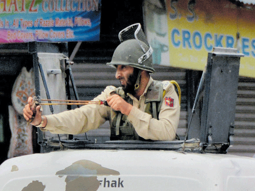 A policeman uses catapult to disperse protesters during a clash over the house arrest of Hurriyat Chairman Syed Ali Shah Geelani at Nowhatta Chowk in Srinagar on Friday. PTI Photo