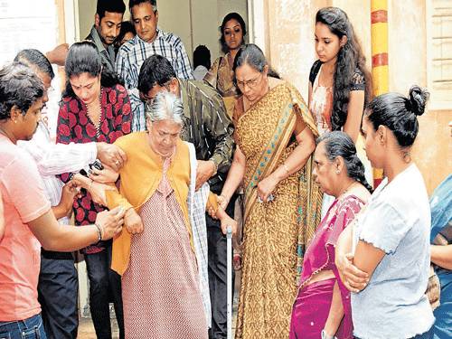 An elderly woman struggles to step down from an election booth after casting her vote as other voters help her at BM Primary School in Malleswaram. DH photo