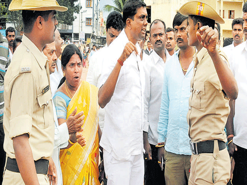 A worker of a political party argues with policemen at a  KR Puram booth.