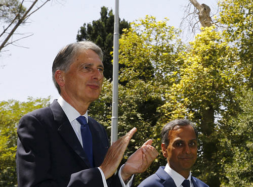 Britain's Foreign Secretary Philip Hammond (L) and non-resident charge d'affaires Ajay Sharma watch as the Union flag is raised at the British Embassy in Tehran, Iran. Reuters photo