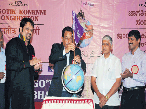 Deputy Chief Minister of Goa Francis D'Souza instals the Konkani flag on a globe to inaugurate the second global conclave on Konkani Language Plan at Kalaangann in Mangaluru on Sunday. DH photo