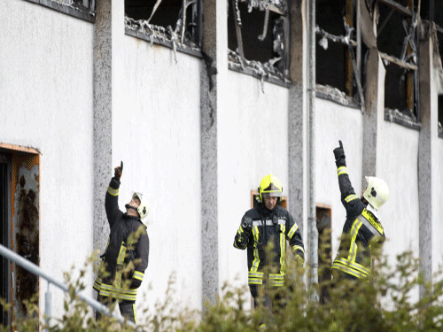 Firefighters stand in front of a burned gymnasium where asylum seekers are due to be housed in Nauen, Germany. Reuters photo