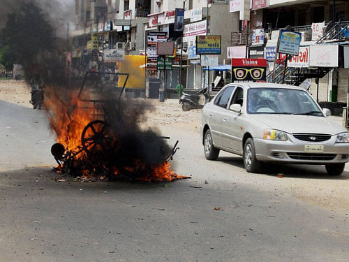Patel community members set ablaze motor-bikes to block a road during their agitation for reservation in Ahmedabad on Wednesday. PTI Photo