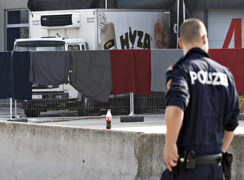 A police officer walks by a truck discovered abandoned on an Austrian motorway containing more than 70 bodies as it sits at a customs building with refrigeration facilities in the village of Nickelsdorf. Reuters photo