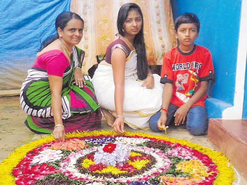 Women giving final touches to a Pookalam, the rangoli of flower petals, as part of Onam celebrations near Bilagula of Mudigere taluk on Friday. Dh photo