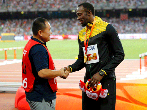 Usain Bolt of Jamaica (R), gold medalist, shakes hands with Song Tao, a cameraman of CCTV, whose Segway lost control and hit Bolt, after the podium ceremony for the men's 200 metres event during the 15th IAAF World Championships at the National Stadium in Beijing, China, August 28, 2015. REUTERS