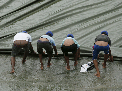 Ground workers pull the covers to cover the ground as the match was stopped due to rain, on the first day of third and final test cricket match between India and Sri Lanka in Colombo August 28, 2015. REUTERS