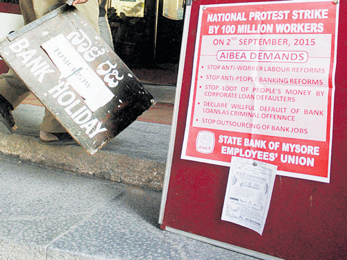 A worker walks past a poster on Wednesday's strike, put up at the head office of State Bank of Mysore in Bengaluru on Tuesday. KPN