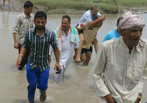In the picture, the legislator from Chhamb Assembly seat, is seen crossing the rivulet on the back of his PSO. Image Courtesy Twitter.