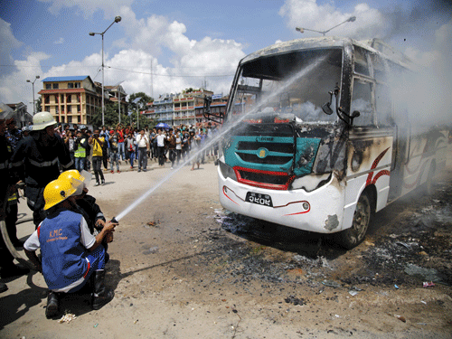 Firefighters try to douse fire set by unidentified protesters on a passenger bus during the nationwide strike, called by the opposition parties against the proposed constitution, in Kathmandu . REUTERS