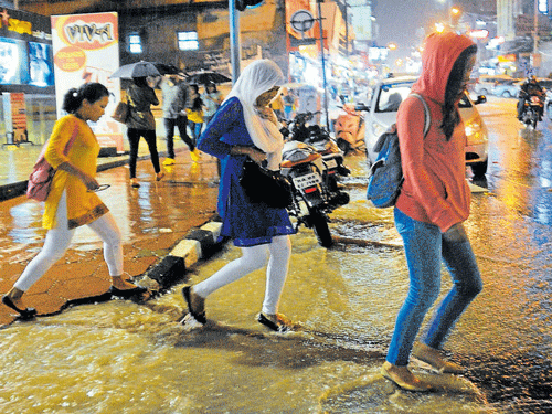 evening showers Pedestrians had a tough time walking on the waterlogged Brigade Road on Sunday. DH PHOTO