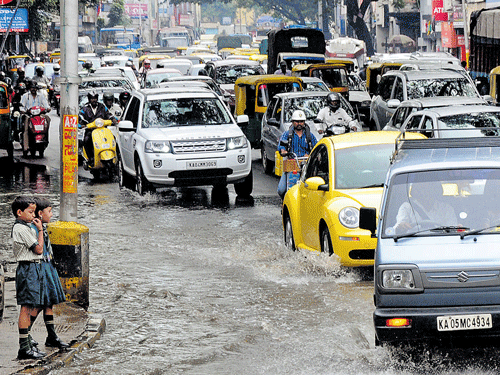 Vehicles struggle to negotiate the waterlogged JC Road after sudden rains lashed the City on Monday. DH PHOTO