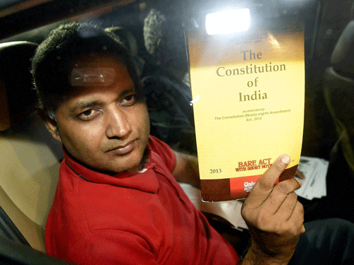 AAP MLA Somnath Bharti shows a copy of the Constitution as he arrives to surrender in New Delhi on Monday. PTI