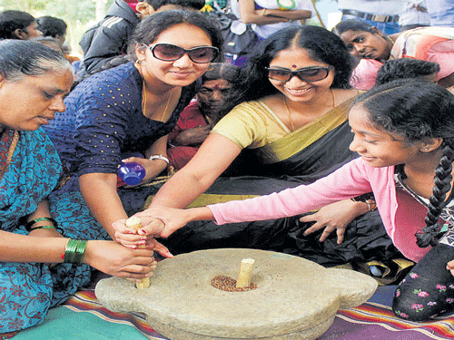 Visitors try their hand  at a grinding stone at the two-day Halli Habba in the City on Saturday. Dh photo