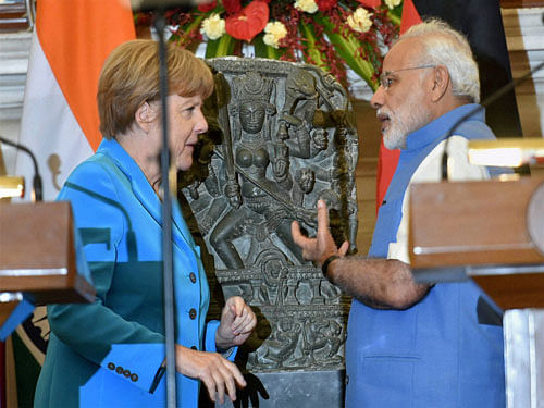 Prime Minister Narendra Modi and German Chancellor Angela Merkel with a 10th centery idol of Hindu Goddess Durga, that was returned by Germany, at Hyderabad House in New Delhi on Monday. PTI Photo