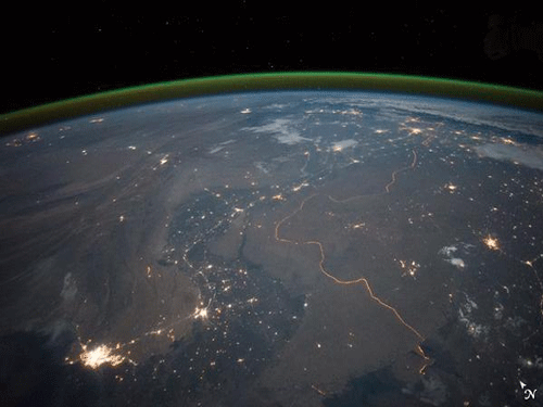 The winding border between India and Pakistan can be seen lit by security lights that have a distinct orange tone. Image Courtesy Twitter.