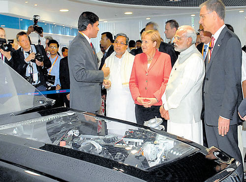 TECH IN ACTION: Prime Minister Narendra Modi, German Chancellor Angela Merkel and Karnataka Chief Minister Siddaramaiah inspect a car engine during their visit to the Bosch Engineering Centre in Bengaluru on Tuesday. DH PHOTO