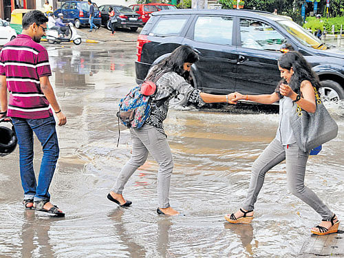 People try tomake their way on the flooded roads in Vittal Mallya Road, after rains lashed the City on Sunday. DH PHOTO