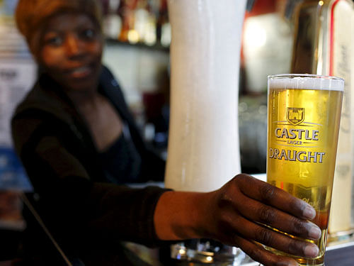 A bartender serves a beer produced by brewing company SAB Miller at a bar in Cape Town, in this file picture taken September 16, 2015. SABMiller accepted a takeover proposal at the fifth time of asking after Anheuser-Busch InBev, the world's largest brewer, set out a cash-and-share package currently worth 69 billion pounds ($106 billion). The deal to create a brewer making almost a third of the world's beer would rank in the top five mergers in corporate history and be the largest takeover of a UK company. REUTERS