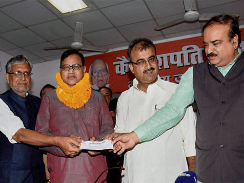BJP Bihar in-charge Ananth Kumar, senior party leader Sushil Kumar Modi and state president Mangal Pandey giving party member slip to JD(U) former minister Bhim Singh as he joins the party in Patna on Friday. PTI photo