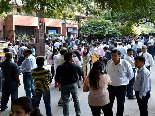 Employees come out of their offices after an earthquake in New Delhi on Monday. PTI Photo