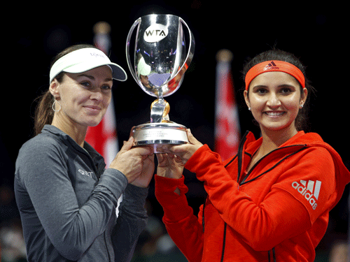 Martina Hingis of Switzerland and Sania Mirza of India celebrate with their trophy after defeating Garbine Muguruza of Spain and compatriot Carla Suarez Navarro in their women's doubles finals tennis match of the WTA Finals at the Singapore Indoor Stadium November 1, 2015. Reuters Photo.