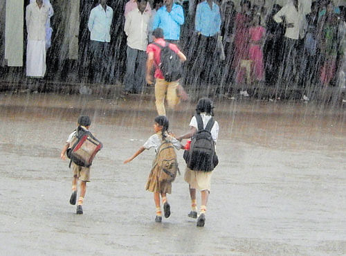 Children run for cover as it rains heavily in Shikaripur, Shivamogga district, on Monday. DH PHOTO