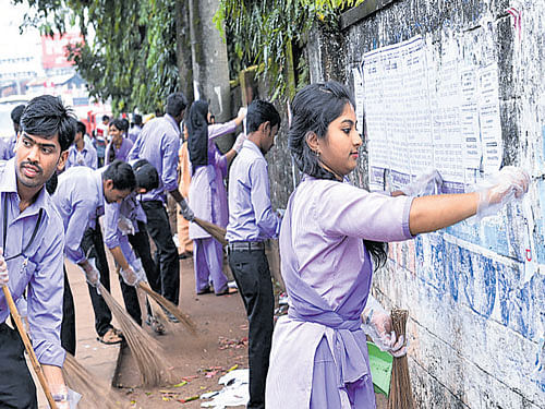 Students remove the posters on the walls on the streets on Sunday. DH photo