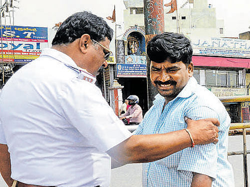 A traffic policeman catches a jaywalker on Dhanvantari Road at Majestic on Tuesday. DH photo