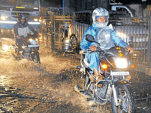 Motorcyclists negotiate a waterlogged road as rains lashed the City on Tuesday evening. DH photo