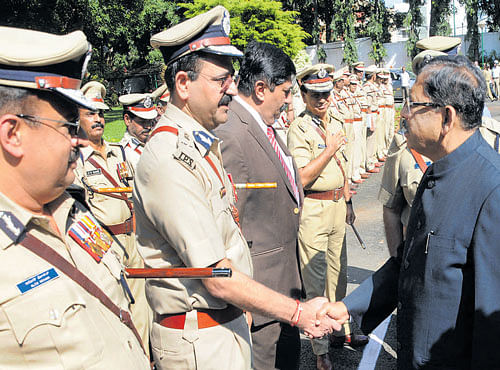 Home Minister G Parameshwara greets police officers as he arrives at the Police Headquarters in Bengaluru on Friday, for a meeting with the top cops. DH PHOTO