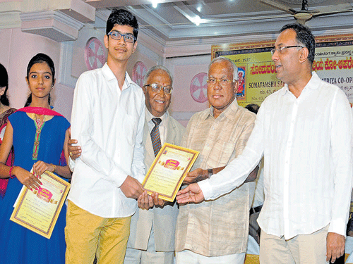 Minister for Food and Civil Supplies Dinesh Gundu Rao gives away scholarships to students during a programme organised by the Somavamsha Sahasrarjuna Kshatriya Co-operative Society Limited  in Bengaluru on Sunday. Former minister P G R Sindhia and Society president D Gangadharsa look on. dh photo