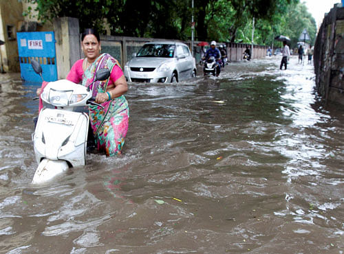People wade through a waterlogged street after heavy rains in Chennai on Monday. Heavy rains continue to lash several parts of the city as the Meteorological Department alerted a cyclone warning on the Bay of Bengal coast. PTI Photo