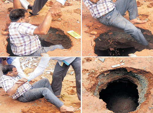 SLIP AND FALL: Nandakumar, 55, caves into a cavity on the footpath near Sir M Visvesvaraya Metro station in The City on Thursday. He was rescued by passersby. DH PHOTO