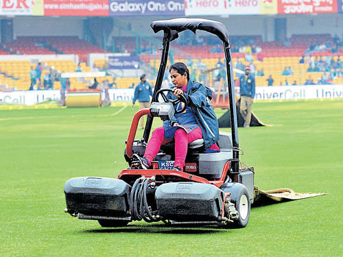KSCA ground staff Jecintha dries the ground at Chinnaswamy Stadium in Bengaluru on Sunday. DH Photo/Srikanta Sharma R