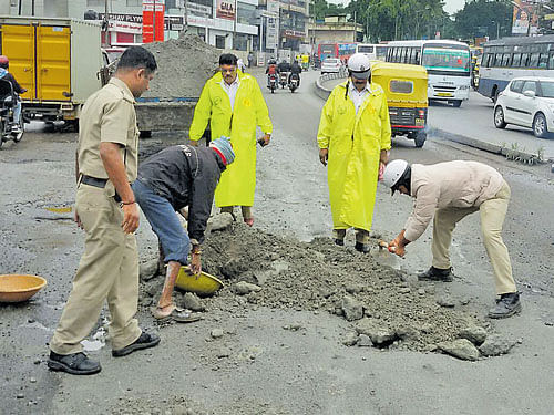 Doing someone else's job: Traffic police fill potholes with jelly powder in Byatarayanapura on Mysuru Road to ensure smooth vehicular flow. Potholes and pits made travelling on Mysuru Road a nightmare on Monday. DH&#8200;PHOTO